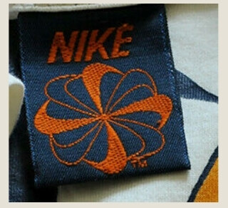 Vintage Nike pinwheel neck tag, orange swooshes arranged in a circle on navy woven fabric