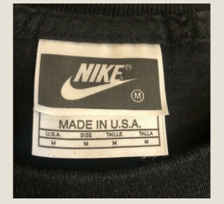 Vintage Nike black tag with light Nike branding on a dark rectangular label