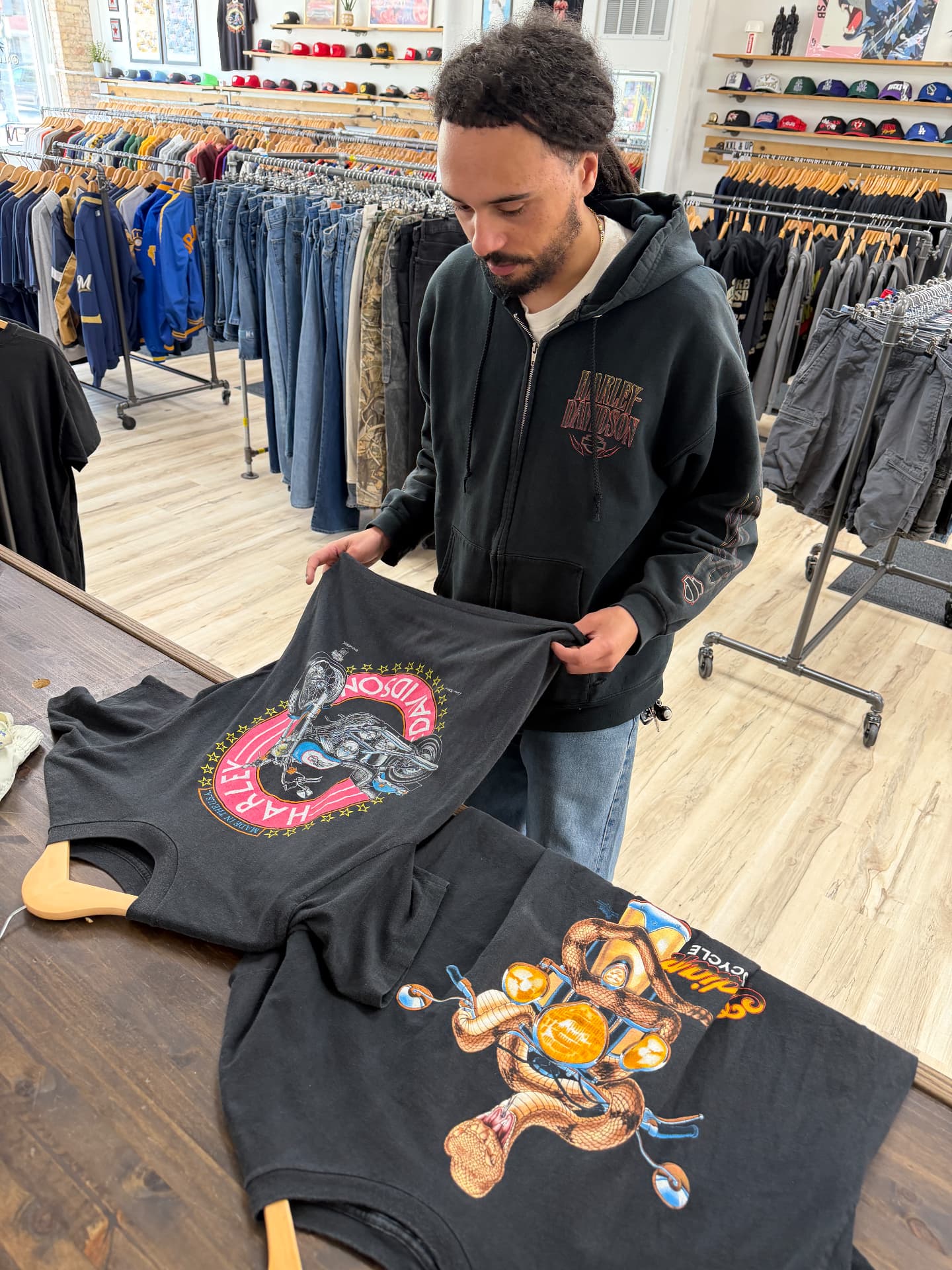 All Goods staff inspecting vintage Harley-Davidson tees at the shop counter